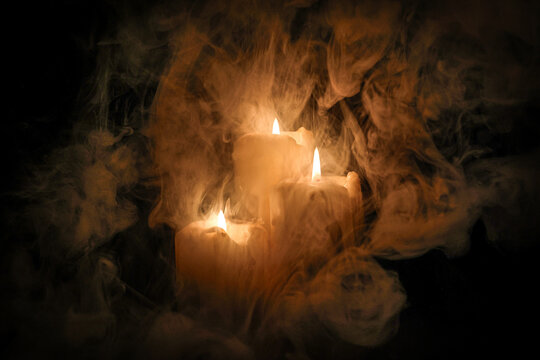 Lit candle flame through heavy smoke fog mist vapour flow twist beautiful mistic