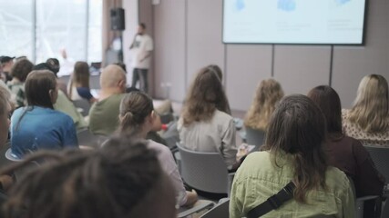 Diverse group of people attentively listening to a speaker during a seminar. The focus is on audience engagement and learning in a conference room environment. - Powered by Adobe