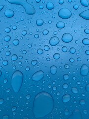 Vertical shot of water drops on an electric blue background. Water texture wallpaper. Perfect organic water shape on a blue background. Big bubbles on a blue surface.