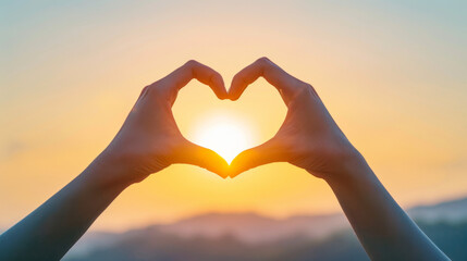Fototapeta premium Hands forming a heart shape against a vibrant sunset in a serene outdoor setting