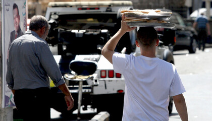 A boy carries a tray of food on his head to deliver it to customers in shops in the commercial area...
