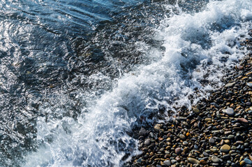 Water sea beach. Wave ocean blue. Stone texture reflection sun. Surface coast pebbles. Abstract light rock background.
