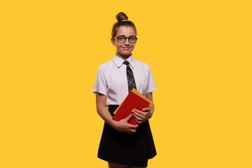 Teen girl holding books, wearing glasses and a school uniform, smiling.