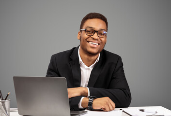 Confident Businessman. Happy black man sitting at desk, smiling at camera over white background, copy space