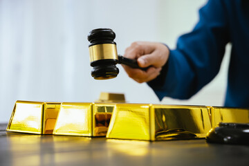 Saving and investment concept, businessman holding gold bars and a lawyer's hammer, thinking about gold laws, gold price