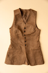 Womens light brown artificial suede vest lies on a peach fuzz background. Slow fashion concept