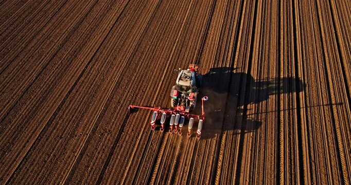 The diligent farmer in his tractor is sowing soybean crops