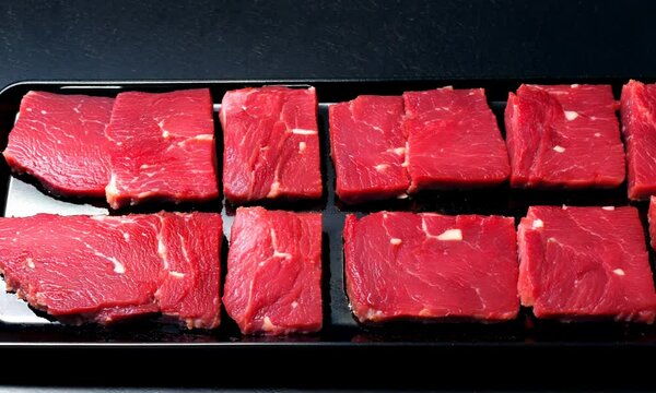 Freezer beefsteak in packaging on black background. Raw beef steak vacuum sealed bag for sell. Beef rib eye steak plastic pack. top view. Video