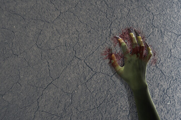 Witch hand with long nail claw is on a ground. The color hand is green and covered in blood. Evil,...