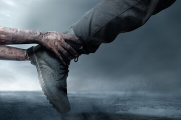 A zombie hand with a bloody wound grabs a human shoe in the foggy fields. Scene has dark and scary....