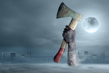 Zombie hands with a bloody wound rising out of ground holding an axe with full moon background....