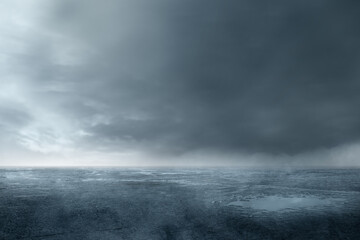 A wet, muddy field with cloudy and dark sky background