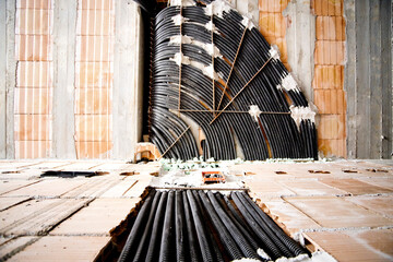 construction site, collection of black corrugated pipes arranged to follow a curved path, used for the electrical system in a rough brick wall