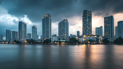 Naklejka premium Skyline of modern Bangkok, Thailand. Majestic skyscrapers on the waterfront under the cloudy sky at twilight time.