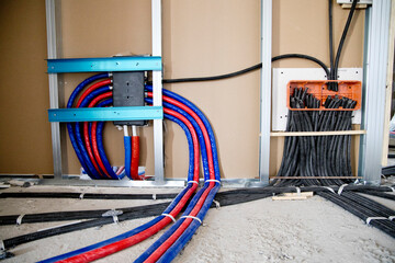 construction site, collection of black corrugated pipes arranged to follow a curved path, used for the electrical system in a rough brick wall