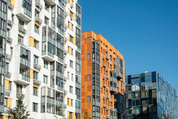 Against the blue sky, modern apartment blocks.