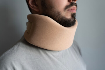 Portrait of young man with cervical collar. Cervical spine stretching and therapy concept. Adult man wearing orthopedic collar. Spinal injury. Neck diseases treatment. Medical collar. Rehabilitation