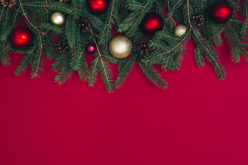 Christmas background with Christmas tree toys, fir branches, and inscription. Red background.