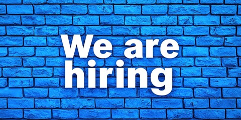 Obraz premium We are hiring text on the blue brick wall. Concept of employment. Generative Ai