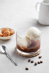 Affogato coffee with vanilla ice cream scoops and  espresso in a glass on a light  background with coffee beans, jug and cookies.