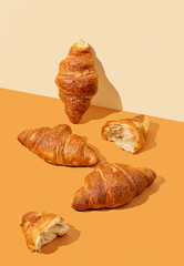 Fresh croissants on yellow and orange background. Creative diagonal trendy layout and healthy food or french breakfast concept.