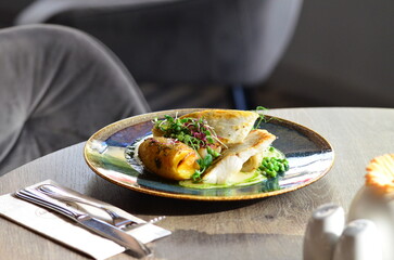 close up view of served food in restaurant on wooden table, pike perch with sauce and baked potato,...