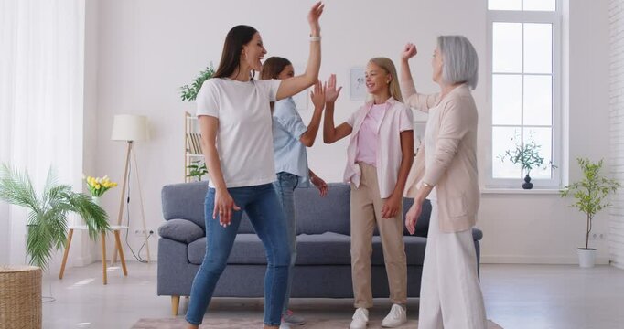 Female happy three generations of women family fun picture, dancing cute little teen girls, mom and granny enjoy time at home, smiling mother, daughter and grandmother spend weekend together