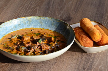 close up view of food served in restaurant on wooden table, mushroom goulash or ragout with fried...