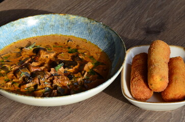 close up view of food served in restaurant on wooden table, mushroom goulash or ragout with fried croquette, czech food