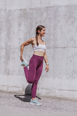 Vertical shot of a female runner stretching her legs after a running. Fit female runner in sports...