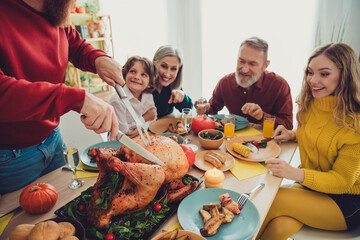 Photo of big family celebrating thanksgiving day man cutting traditional dish baked turkey indoors