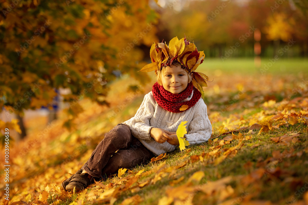 Poster Adorable little child, blond boy with crown from leaves in park on autumn day.