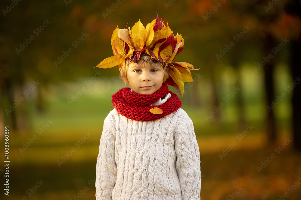 Poster Adorable little child, blond boy with crown from leaves in park on autumn day.