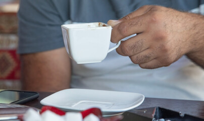 Caucasian man drinking coffee in the outdoor cafe.