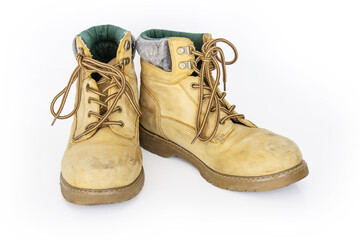 Vintage yellow leather hiking boots with laces in a worn look. Beige used military shoes with thick soles. Isolated on white background. Studio light. Copy space