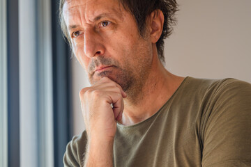 Headshot portrait of mature adult male thinking and looking out the window