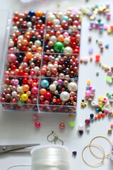 Colorful beads, letter beads, threads and other jewelry making supplies on white background. Making friendship bracelets concept. Selective focus.