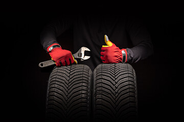 Car tire service and hands of mechanic holding new tyre on black background with copy space for text © ValentinValkov