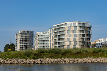 Rising exterior facades of newly build luxury apartment buildings along riverside of river IJssel seen from the water. Engineering and urban development real estate concept.