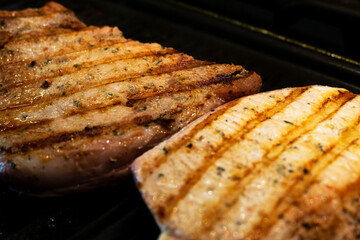 Grilled Pork steaks, neck meat on grill pan. Black background. Top view.