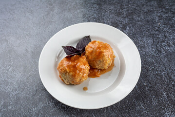 A plate of meatballs with a sprig of basil on top
