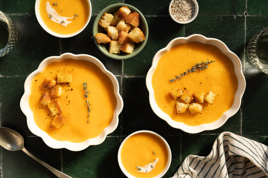Variety of pumpkin soup servings with croutons and herbs