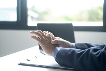 Businessman in office Using a laptop to work so hard that it hurts his wrists, hand massage physiotherapy other side is sore and numb, Guillain-Barre Syndrome, side effect of vaccination