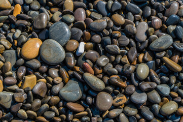 Wet sea pebbles close-up. Rocky beach on the sea, ocean, river, lake, pond. Natural background for design.