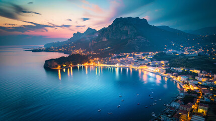 Aerial view of a city by the sea at night with a mountain in background