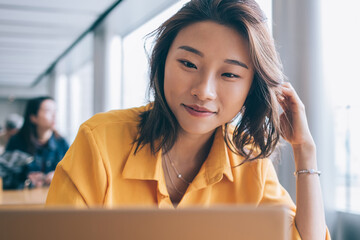 Positive female freelancer downloading media files during distance job with startup project using...