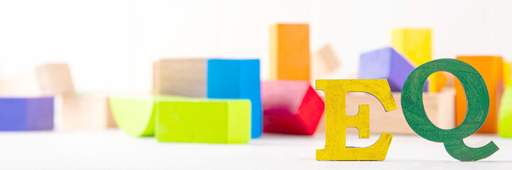 Kids EQ, child emotional quotient concept with wooden cubes children toys on background, wooden cubes kids toys on background, letters text lettering EQ in the foreground