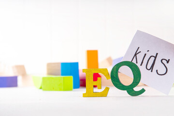 Kids EQ, child emotional quotient concept with wooden cubes children toys on background, wooden cubes kids toys on background, letters text lettering EQ in the foreground