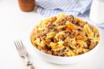Easy homemade pasta with minced meat. One pot pasta with ground beef and autumn vegetables, in portioned plate on kitchen table