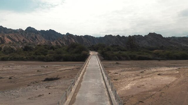 Drone flight over a narrow bridge crossing the Cachalqui River in the Quebradas de las Flechas, Salta Province, Argentina. Route 40.
